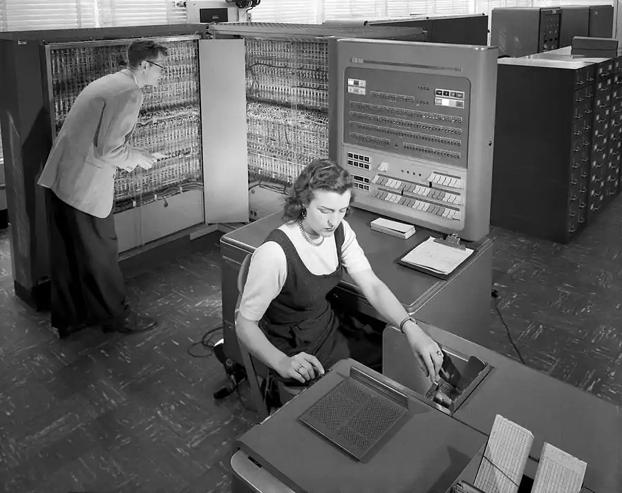 Photo prise en mars 1957 au Centre de recherche Langley capturant l"image d'une femme et d'un homme qui travaillent sur machine de traitement électronique de données IBM type 704 utilisée pour la recherche aéronautique